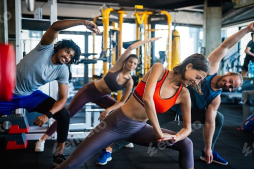 Preview: Group of young people doing exercises in gym