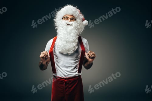 Preview: happy santa claus in eyeglasses holding suspenders standing isolated on grey background