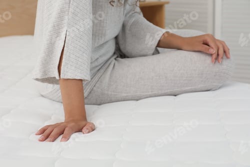 Preview: African American woman sitting on soft mattress in bedroom, closeup