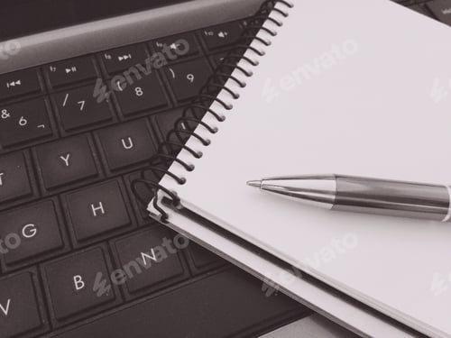 Preview: Monochromatic notepad and pen on top of a computer keyboard