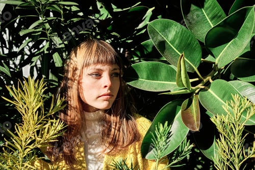 Preview: Portrait of a young blonde caucasian girl with blue eyes among the green plants of the park