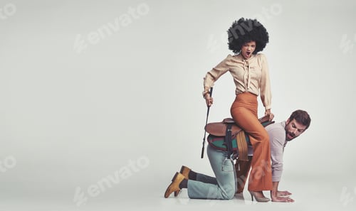 Preview: Shes in charge. A confident young hippie riding an man wearing a saddle in the studio.