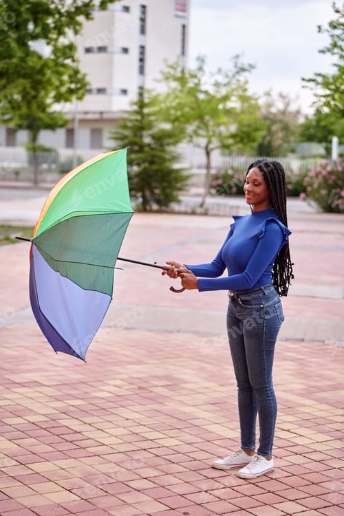 Preview: African American woman opening an umbrella outdoors on the street.