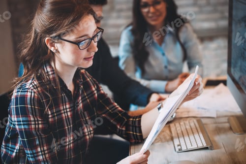 Preview: Happy woman in office looking at blueprint
