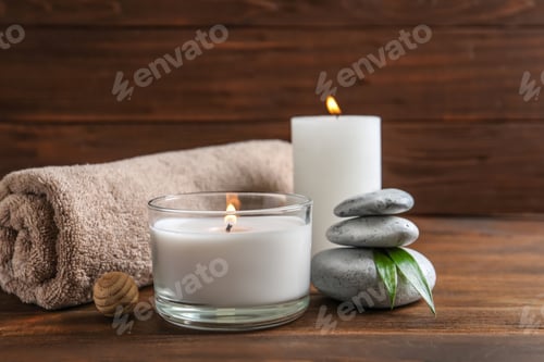 Preview: Beautiful composition with spa stones, towel and burning candles on wooden table