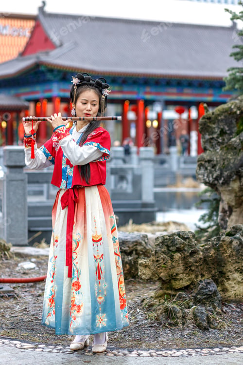 Preview: A Asian woman in traditional red Chinese costume walks,plays the bamboo flute.Chinese New Year