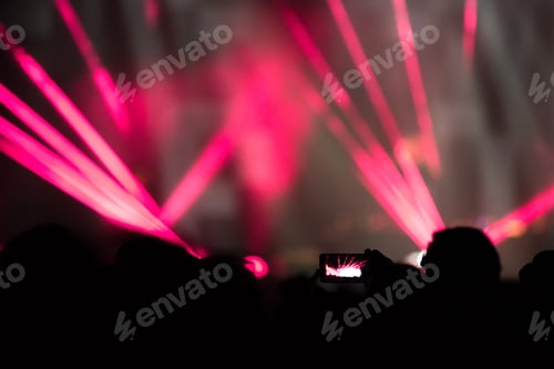 Preview: Silhouette of raised hands holding a smart phone recording music concert