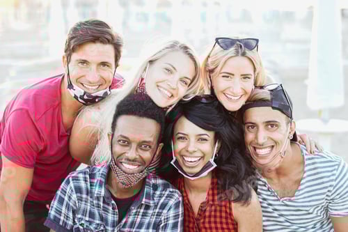 Preview: Group of multiracial friends taking a picture while focusing the camera and smiling with face mask