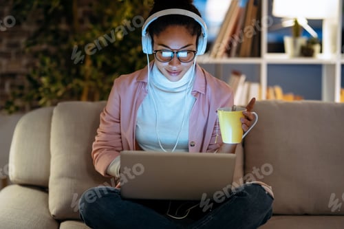 Preview: Pretty entrepreneur woman working with laptop while listening music sitting on couch in the office.
