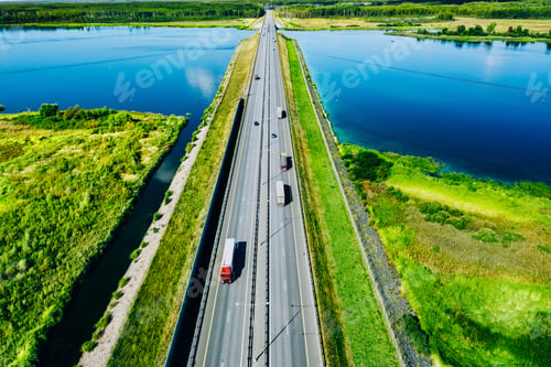 Preview: Aerial drone view of highway asphalt road with cars and cargo trucks over blue water sea.