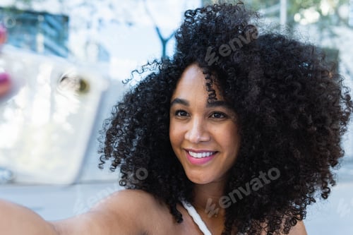 Preview: Happy black woman with curly hair reaching hand to camera