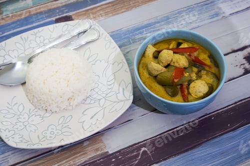 Preview: Green Curry With Fish Balls And Steamed Rice On A Wooden Table