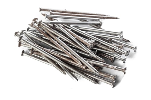 Preview: Metal nails are scattered on a white surface in a varied arrangement