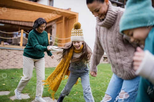 Preview: Two happy sisters with mother and grandmother holding hands and running outdoors in garden in autumn
