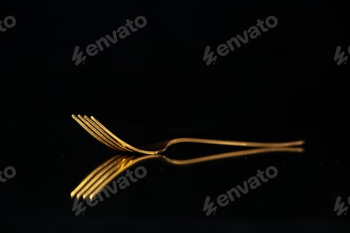 Preview: Close up view of shiny golden fork on black background with free space