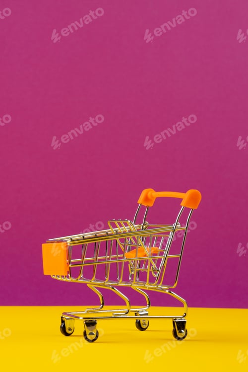 Preview: Composition of shopping cart on pink and yellow background