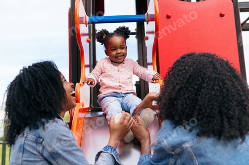 Preview: Twin mothers helping their daughter on playground slide