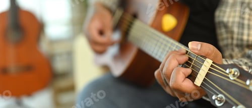 Preview: Close up of young man playing acoustic guitar. Leisure activity and hobby concept