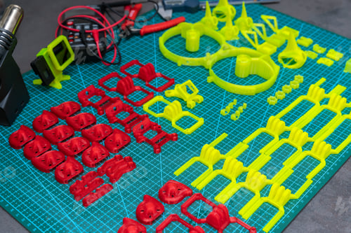 Preview: Multi-colored plastic parts printed on a 3D printer are laid out in rows on a table in a workshop