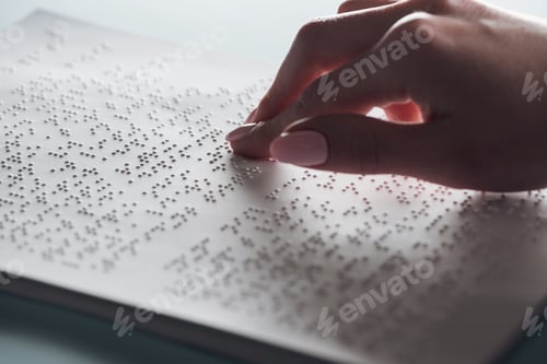 Preview: cropped view of young woman reading braille text on white paper