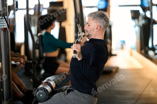 Preview: Man performing lat pulldown exercise in gym