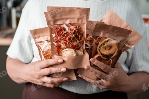 Preview: Several paper packages with homemade dried fruits in hands of housewife