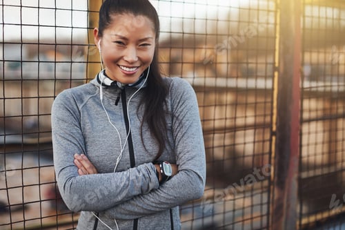 Preview: Young Asian woman in sportswear smiling while standing outside