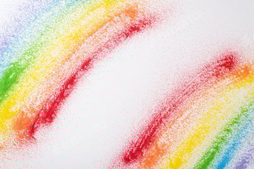 Preview: Vibrant sand flag, LGBT history month symbol. Top view of rainbow flag made from sand on white