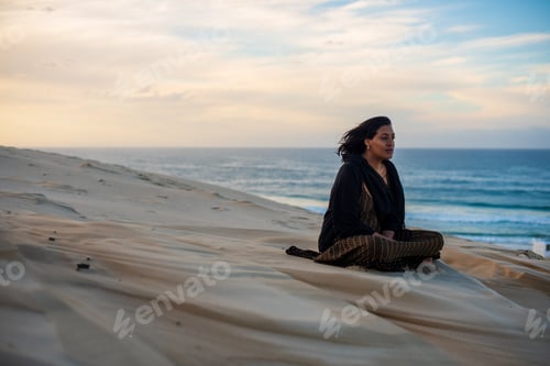 Preview: Woman seen sitting on sand dune while watching the sun rise