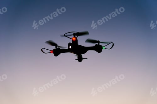 Preview: Toy drone quad copter against sunset sky