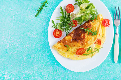 Preview: Breakfast. Omelette with tomatoes, cheese and arugula on white plate.
