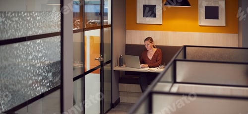 Preview: Businesswoman Working Late In Open Plan Office Using Laptop