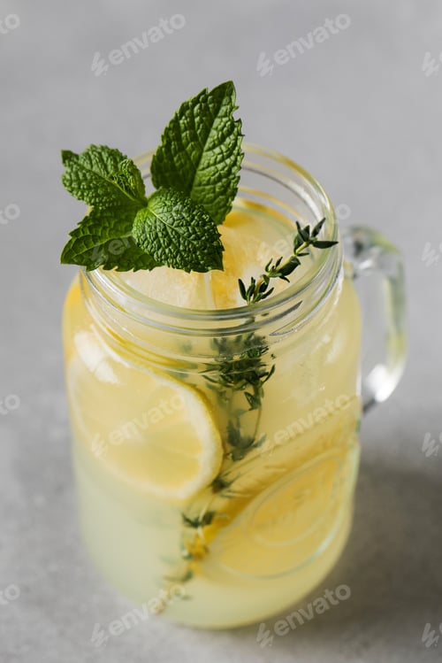 Vorschau: Hausgemachte Limonade mit frischen Zitronenscheiben und Minzblättern in einem Glas. Ein erfrischendes Sommergetränk.