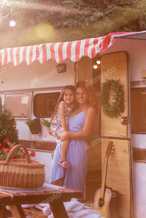 Preview: beautiful red-haired young mother gently holds, hugs little daughter in arms near trailer truck
