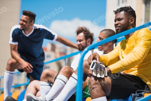 Preview: multicultural soccer team sitting on stadium during soccer match