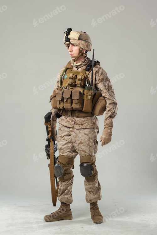 Preview: Soldier in military gear stands with weapon in studio setting during daytime