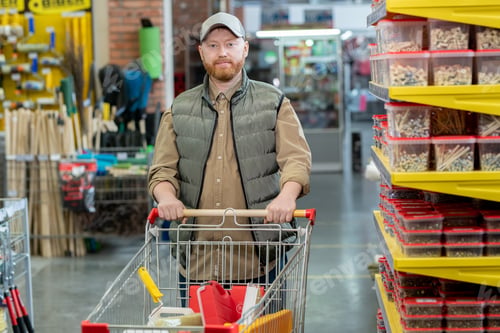 Preview: Happy middle aged man walking along displays in hardware supermarket