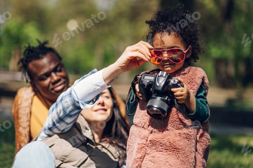 Vorschau: Schöne gemischtrassige Familie mit einer Digitalkamera im Park.