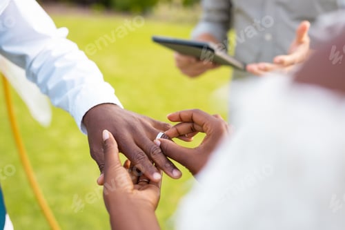 Preview: Close up of african american couple putting ring during wedding