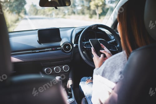 Preview: Closeup image of a woman using mobile phone while driving a car