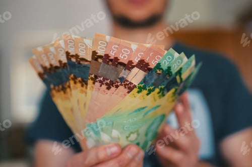 Preview: Midsection of man holding banknotes of Canadian dollars