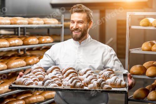 Preview: Handsome baker holding tray full of freshly baked croisants