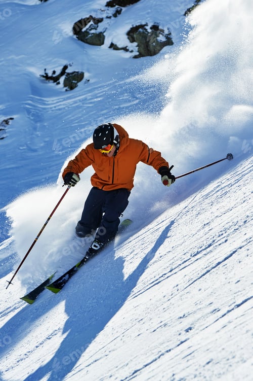 Preview: Skier in action carving through fresh powder on a sunny day