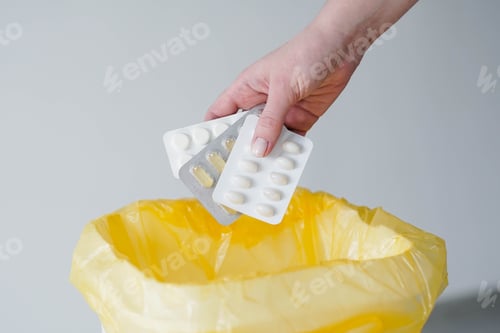 Preview: Woman's hand throws expired blister pills to the trash bin.
