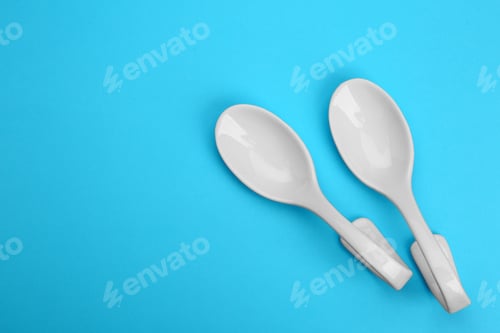 Preview: Clean empty ceramic appetizer spoons on blue background, top view. Space for text