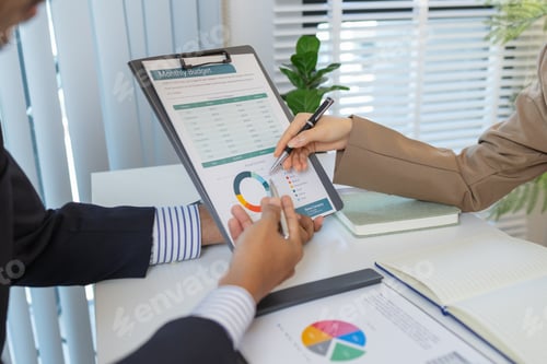 Preview: Business colleagues are engaged in a financial meeting, reviewing colorful charts and reports.