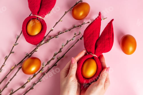 Preview: Golden Easter egg in hand on a pink background. Happy spring holiday.