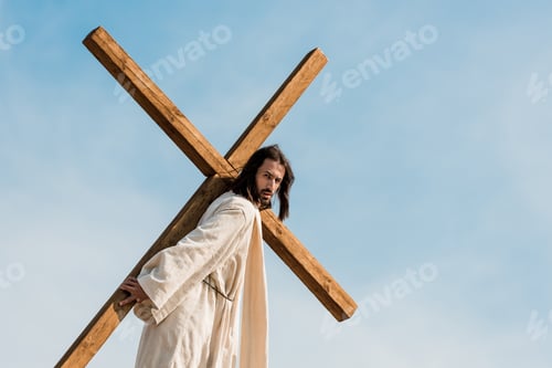 Preview: bearded man walking with wooden cross against sky and clouds