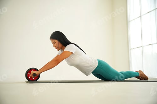 Preview: Woman exercises core strength with an ab wheel in a bright indoor space during the day