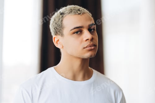 Preview: Portrait of serious Hispanic man with stylish hairstyle looking at camera, fashion model posing
